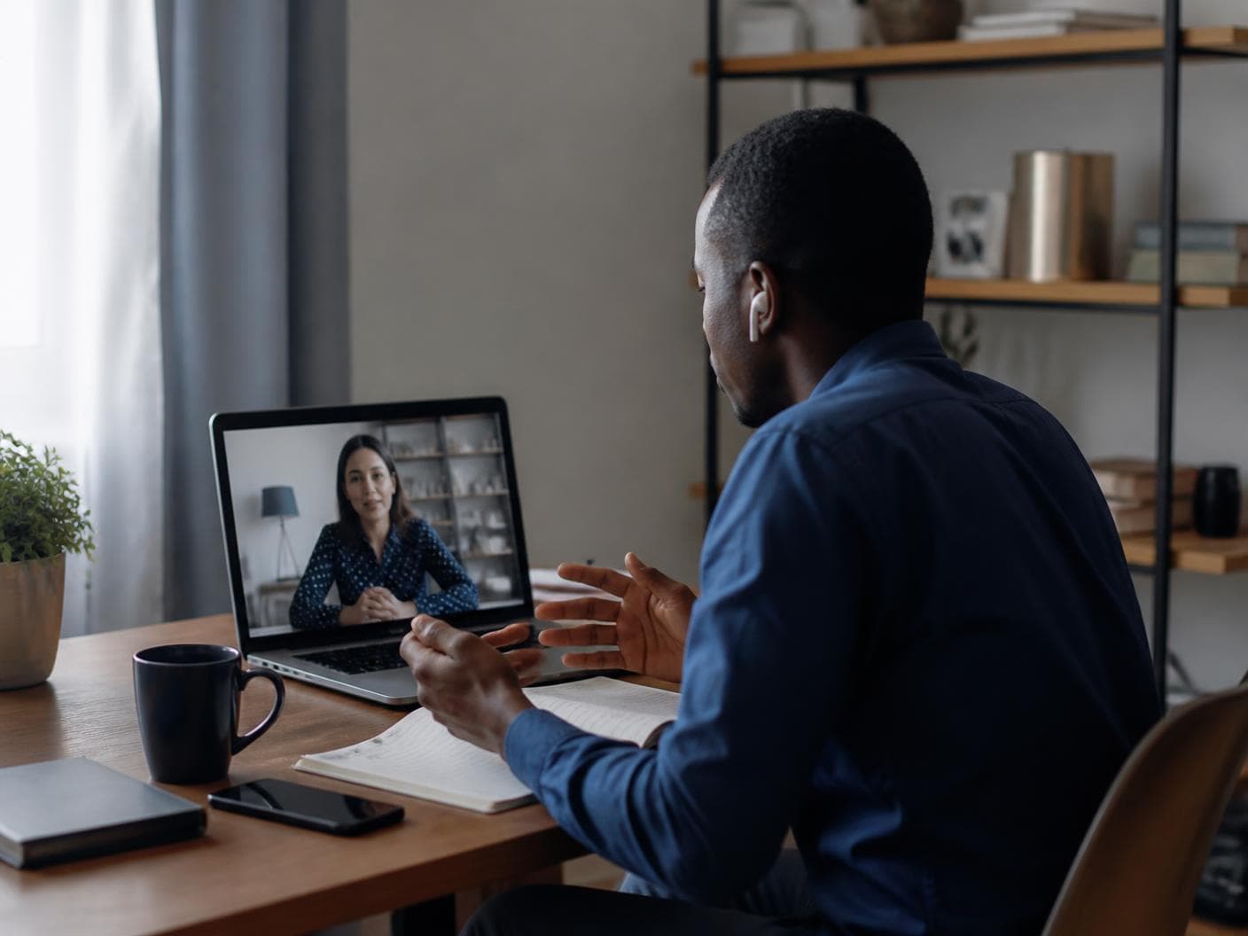 A candidate at his desk, talking with a recruiter on a laptop
